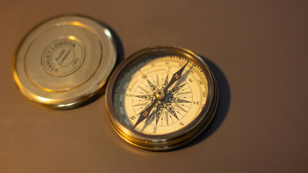 A close-up of a vintage brass compass on a warm brown surface, perfect for exploration themes.